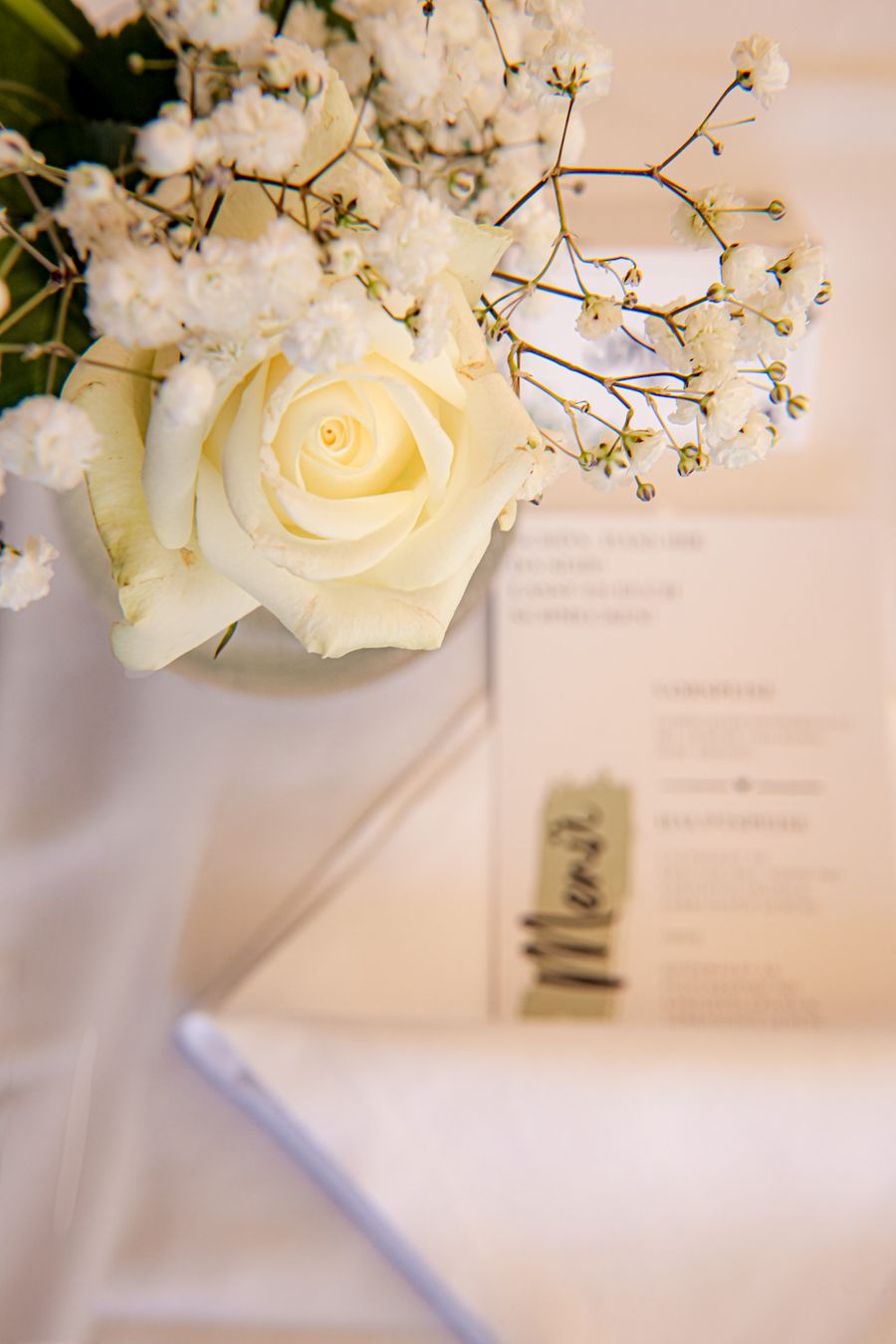 Weiße Rose und Schleierkraut neben der Menükarte auf der Hochzeitstafel